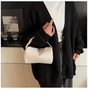 Detailed view of a white textured PU leather pillow bag held by a model in a black cardigan