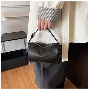 Close-up of minimalist black textured PU leather pillow handbag being held by a model