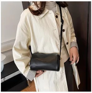 Minimalist black PU leather pillow bag styled with a chic beige coat for a retro look