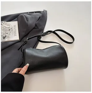 Detailed macro view showing the fine grain texture of a minimalist black PU leather barrel bag.
