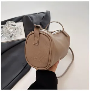 Close-up of a minimalist khaki PU leather cylinder pillow bag with fine grain texture.