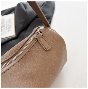 Detail view of the textured PU leather and smooth silver-tone zipper of a minimalist bag.