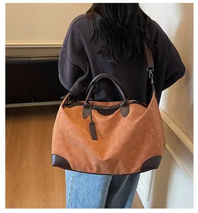 Large brown contrast color travel tote bag shown in detail on a model from back.