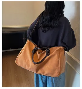 Détail d'un sac de voyage vintage marron porté par une personne à l'intérieur