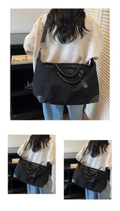 Large minimalist black travel tote bag shown on a female model in back view detail