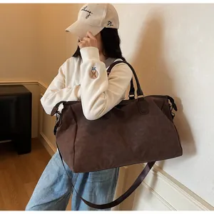 Grand sac de voyage marron imperméable à la mode porté par une personne à l'extérieur