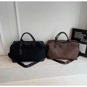 Two large capacity travel duffel bags in black and brown displayed on a marble bench
