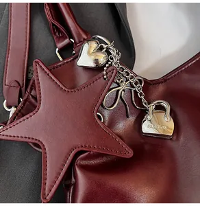 Nahaufnahme der burgunderroten Vintage-Einkaufstasche mit Lederstern und Herzanhängern