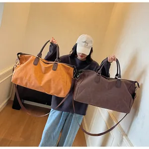 Modèle portant deux grands sacs de voyage étanches en orange et marron foncé chic.
