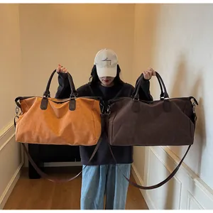 Vue de deux sacs de voyage en daim marron et beige portés par un mannequin