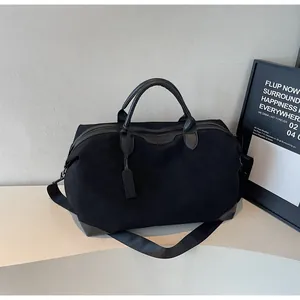 Detailed view of a large black travel tote bag with leather handles and a shoulder strap.