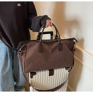 Grand sac de voyage marron posé sur une valise blanche à roulettes