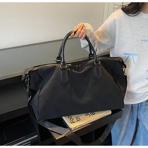 Vue détaillée d'un grand sac de voyage étanche noir tenu à la main pour affaires