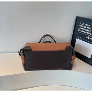 Detailed side view of a large brown and dark brown color-block travel tote bag on display.