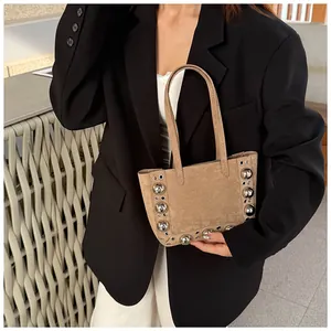 Sac cabas vintage en daim kaki avec gros rivets argentés porté par un mannequin chic