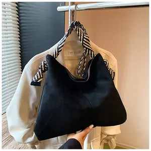Detailed view of black suede tote bag with black and white braided shoulder strap