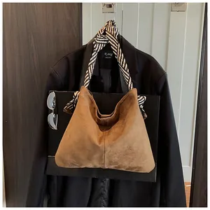 Detailed close-up of a vintage brown suede hobo bag with a stylish striped shoulder strap