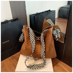 Close-up detail view of a retro matte brown tote bag with a stylish striped woven shoulder strap