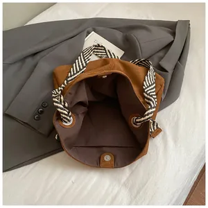 Detail of vintage brown suede tote bag with striped woven strap and interior pocket.