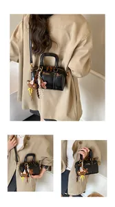 Model carrying a black minimalist Boston bag over a stylish beige trench coat