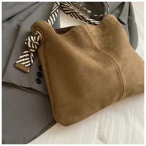 Detail shot of vintage brown suede tote bag with stylish striped woven shoulder strap