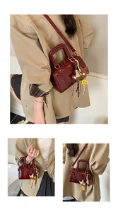 Detail view of burgundy Boston bag with double zipper and cute bear charm pendant.