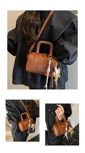 Close-up detail of a brown leather Boston handbag featuring a bear charm accessory