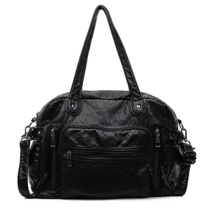 Detailed front view of a black faux leather tote bag with functional multi-zipper pockets.
