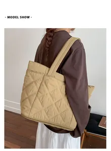 Detail einer großen khakifarbenen Stepptasche mit Rautenmuster, am Modell gezeigt