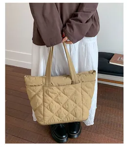 Detailansicht einer großen khakifarbenen gesteppten Tragetasche von einem Model.