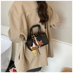 Detailed back view of a woman wearing a black glossy Boston bag with plush charms