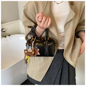 Stylish black patent leather Boston bag with cute bear and star charms held by a model