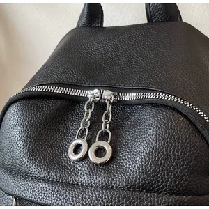 Detailed close-up of a black pebbled leather backpack with stylish silver ring zippers