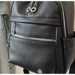 Close-up of black pebbled leather backpack showing silver zippers and hardware.