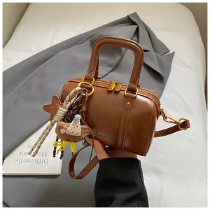 Macro view of brown leather Boston handbag with smooth texture and cute bear charm accessory