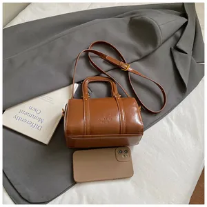 Minimalist brown glossy Boston handbag with top handles and adjustable shoulder strap