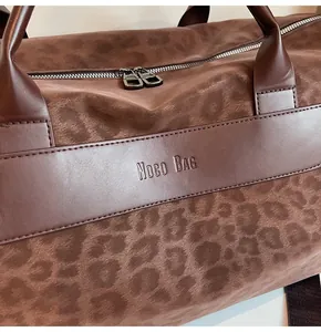 Dettaglio macro della borsa da viaggio leopardata con marchio Noco BAG in rilievo