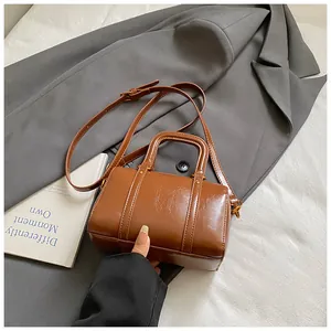 Macro view of a stylish brown Boston bag with top handles and adjustable shoulder strap