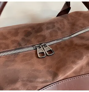 Dettaglio ravvicinato delle doppie cerniere in metallo di una borsa da viaggio marrone