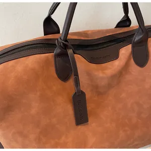 Detailed macro shot of large capacity travel bag handles with an embossed brand tag.