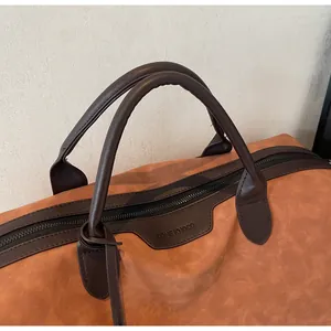 Close-up of durable brown handles and zipper on a stylish camel travel tote bag.