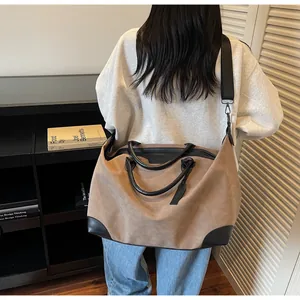 Model wearing a large khaki travel tote bag with black contrast trim and shoulder strap.
