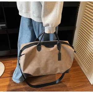 Detailed view of a large khaki travel tote bag with black handles held by a person