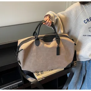 Large capacity suede travel tote bag with black leather accents held by person in studio