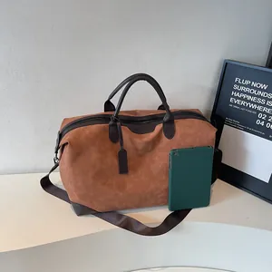 Large brown faux suede travel duffle bag with shoulder strap shown with tablet for scale