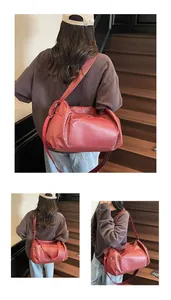 Vedute dettagliate di una grande borsa da viaggio intrecciata bordeaux indossata da modella.