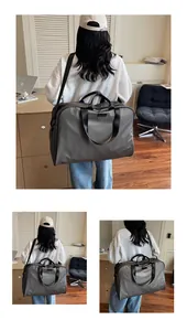 Large capacity charcoal grey travel bag shown carried by a model in an indoor setting