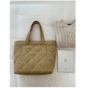 Große khakifarbene Stepptasche im Größenvergleich mit einem iPad und einem Strickpullover