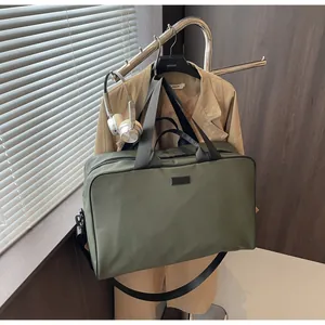 Army green large capacity travel duffel bag hanging on a rack with lifestyle props