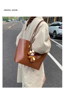 Grand sac cabas en similicuir marron avec breloque ours en peluche à l'épaule.